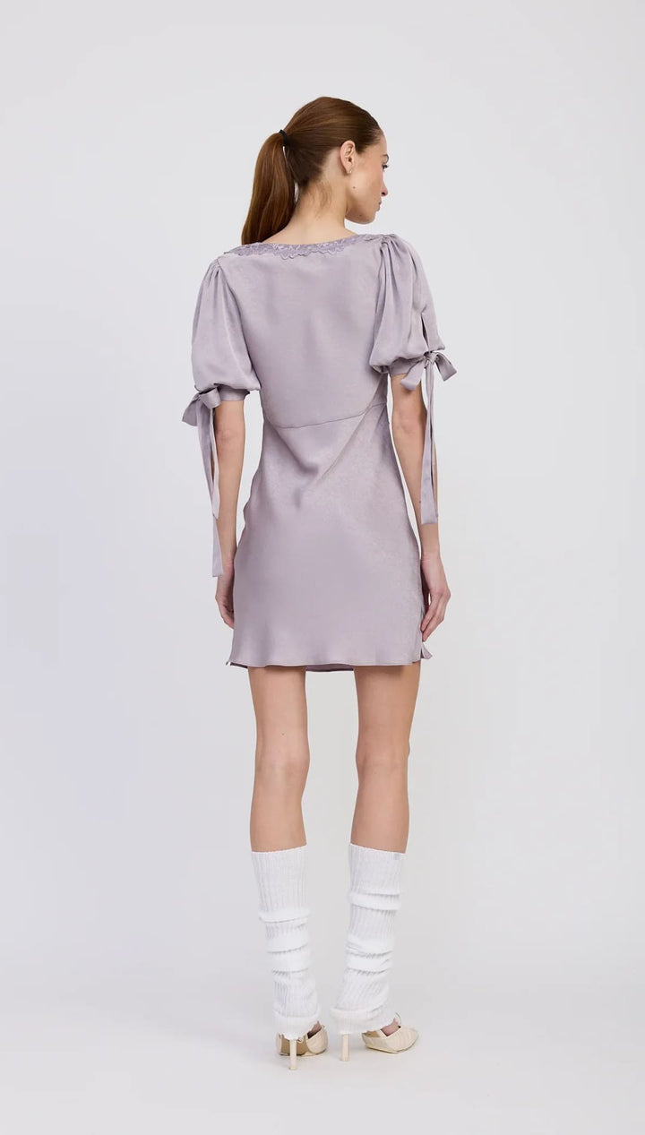 A light purple satin mini dress with puff sleeves and tie details.
