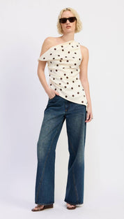 Off-shoulder cream top with black polka dots and a ruched, asymmetrical design.