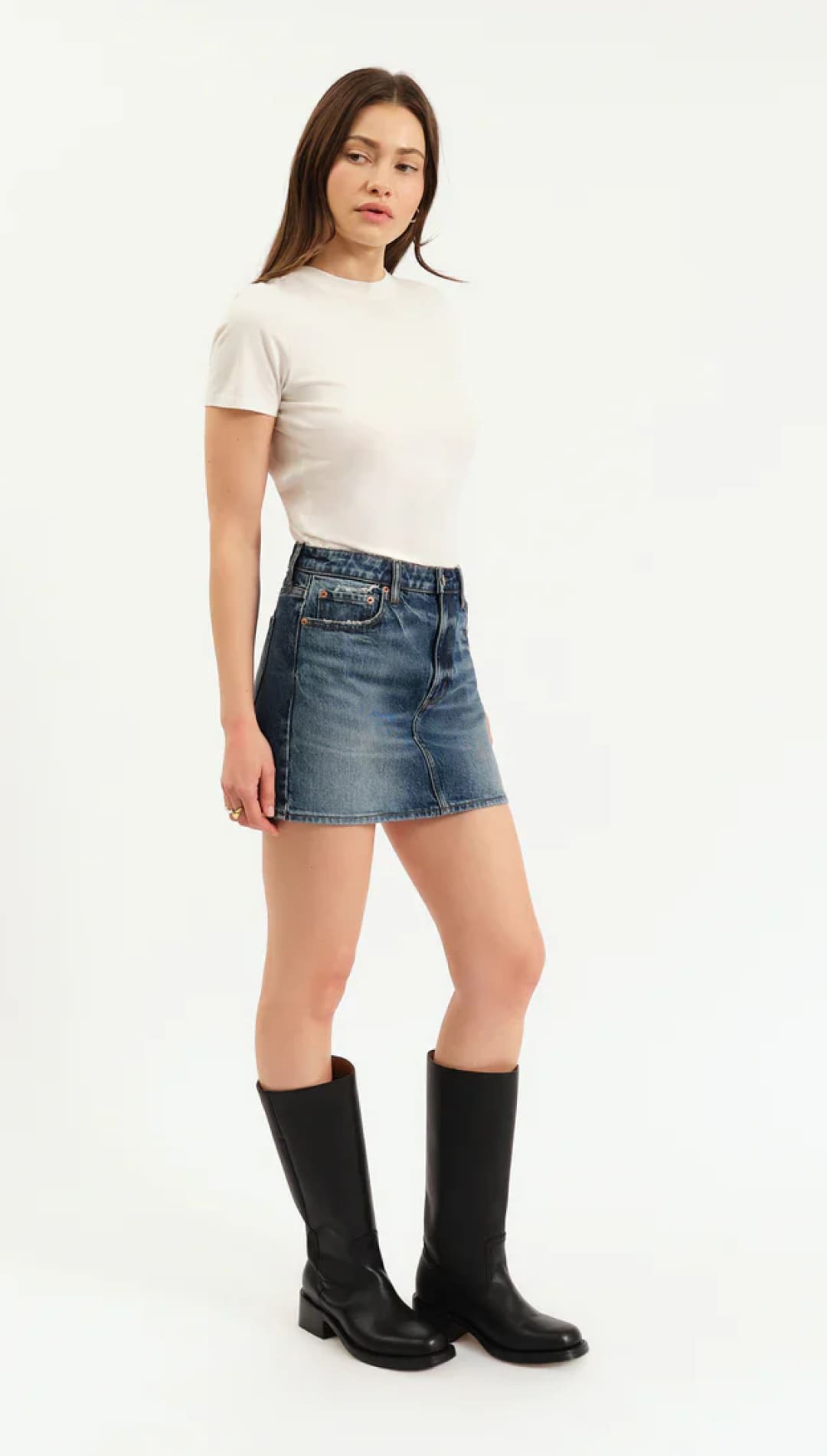 Woman modeling a white short-sleeve t-shirt, blue denim mini-skirt, and black knee-high boots.
