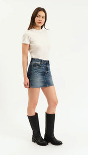 Woman modeling a white short-sleeve t-shirt, blue denim mini-skirt, and black knee-high boots.