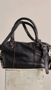 Black leather satchel with dual top handles and a detachable shoulder strap.