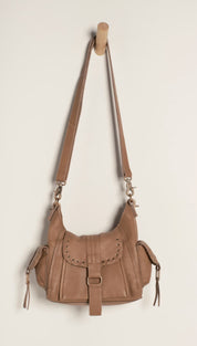 Tan leather crossbody bag with a flap closure, decorative stitching and tassels on the sides.