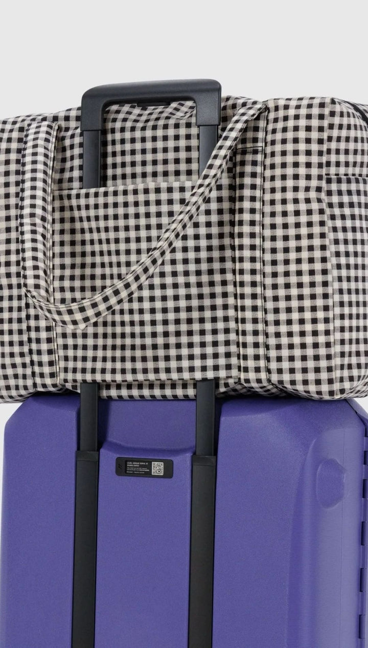 Gingham tote bag on purple suitcase.