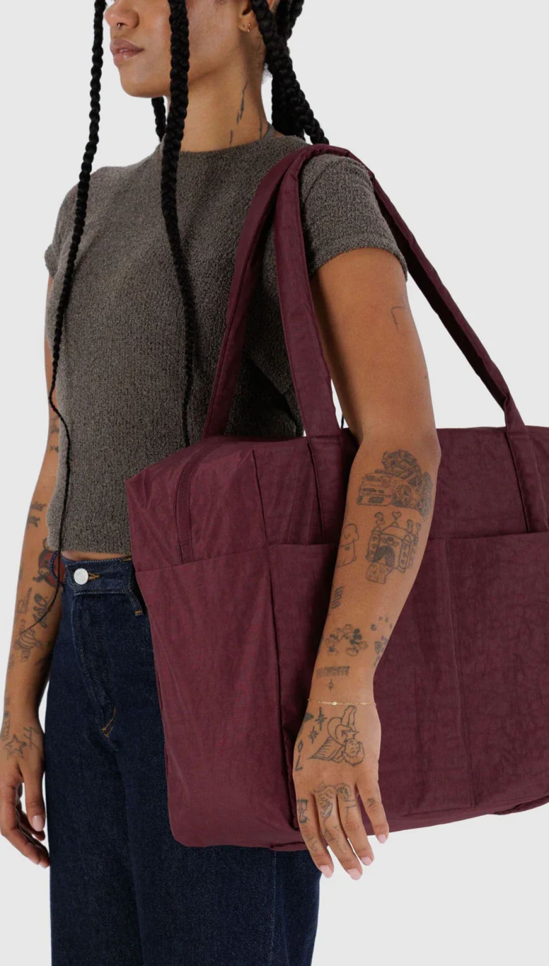 Burgundy tote bag with black handles and pockets, likely made of canvas or similar durable material.