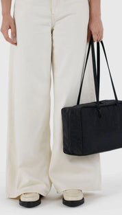 Black rectangular tote bag with long handles and structured design.