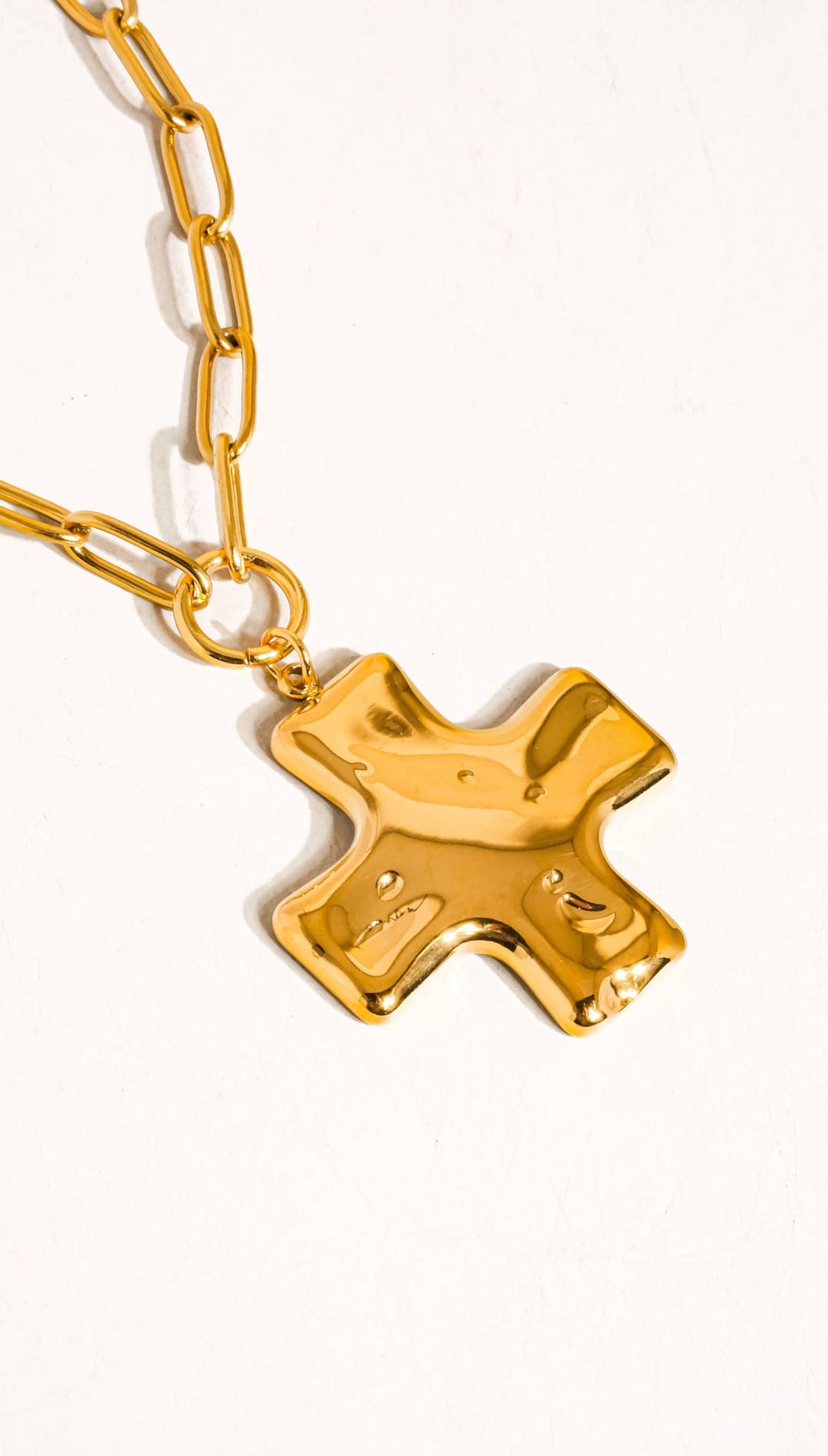 Gold-toned, chunky chain necklace featuring a bold, sculptural cross pendant with a glossy metallic finish.