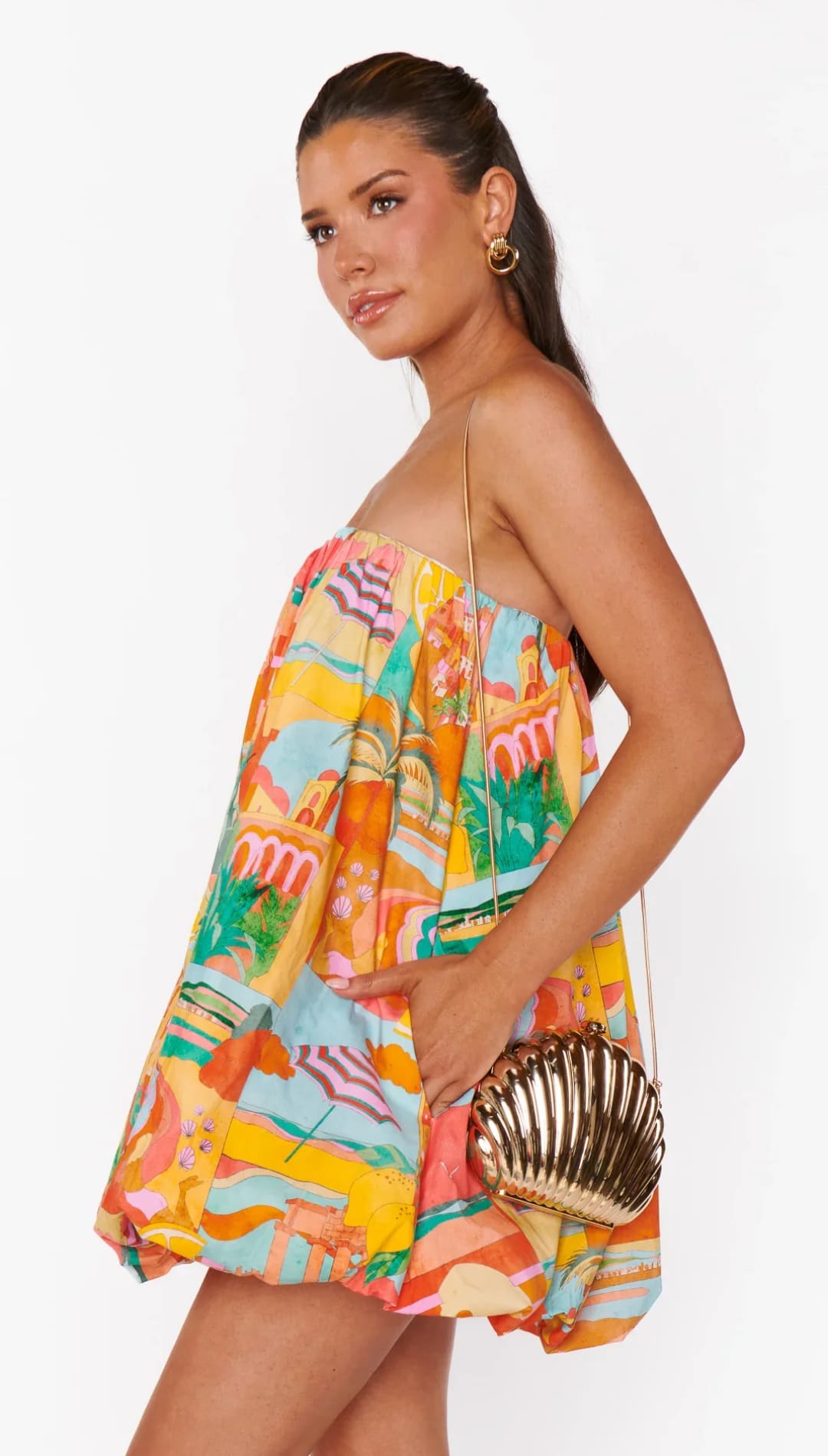 Woman in colorful strapless dress with seashell purse.