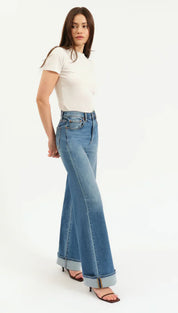High-waisted denim jeans with rolled hem and black sandals.