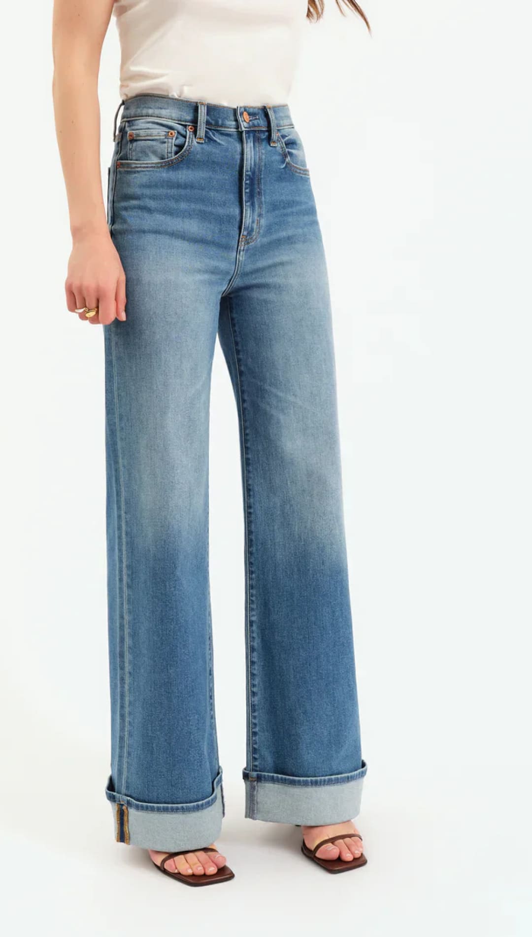 High-waisted light blue denim jeans with rolled cuffs and decorative stitching.
