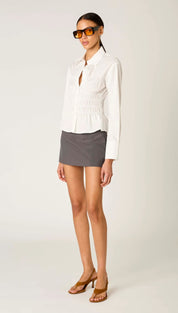 White long-sleeved blouse with a smocked waist and button-down front