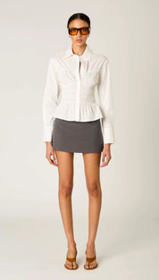 White structured blouse with subtle pleating and peplum hem