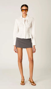 White structured blouse with smocked detailing and peplum hem.