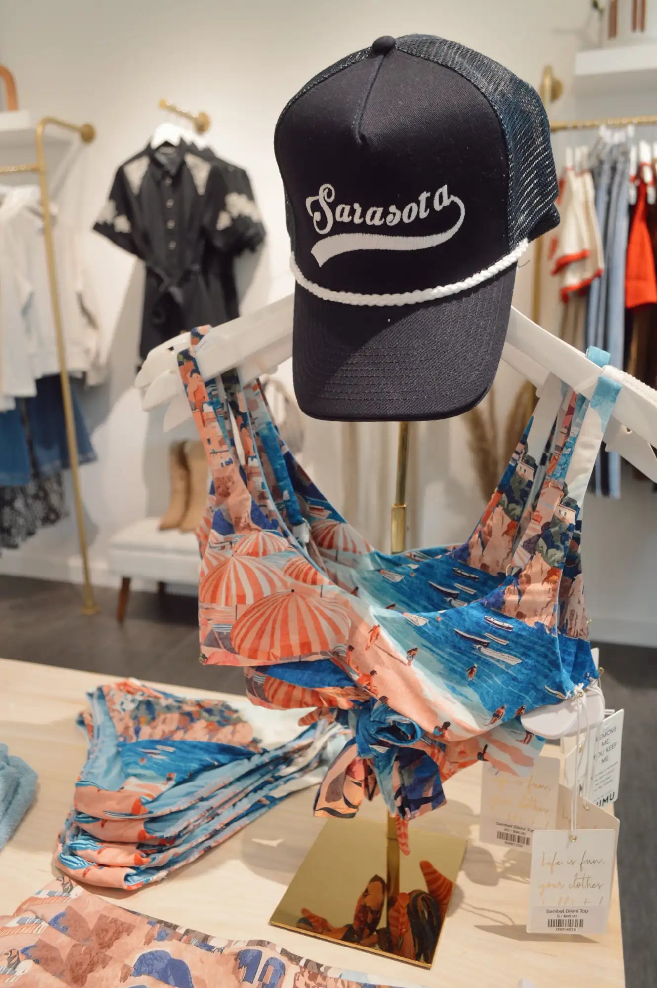 Black and navy mesh trucker hat with white cursive ’sarasota’ lettering across the front.