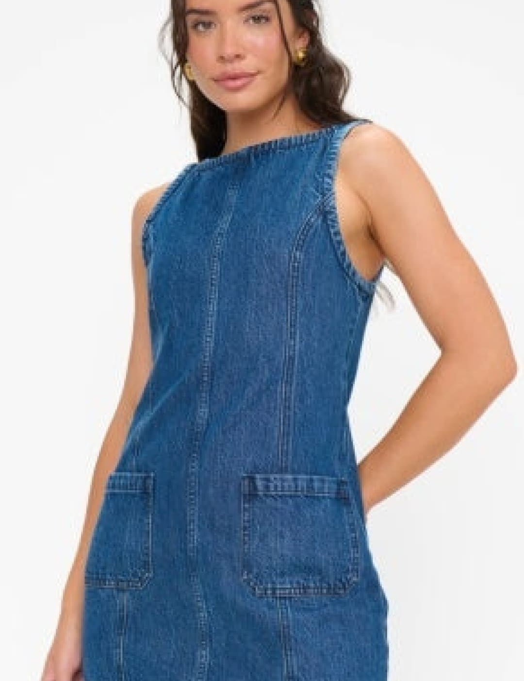 A sleeveless denim dress in a medium blue wash with two front patch pockets and a straight hemline.