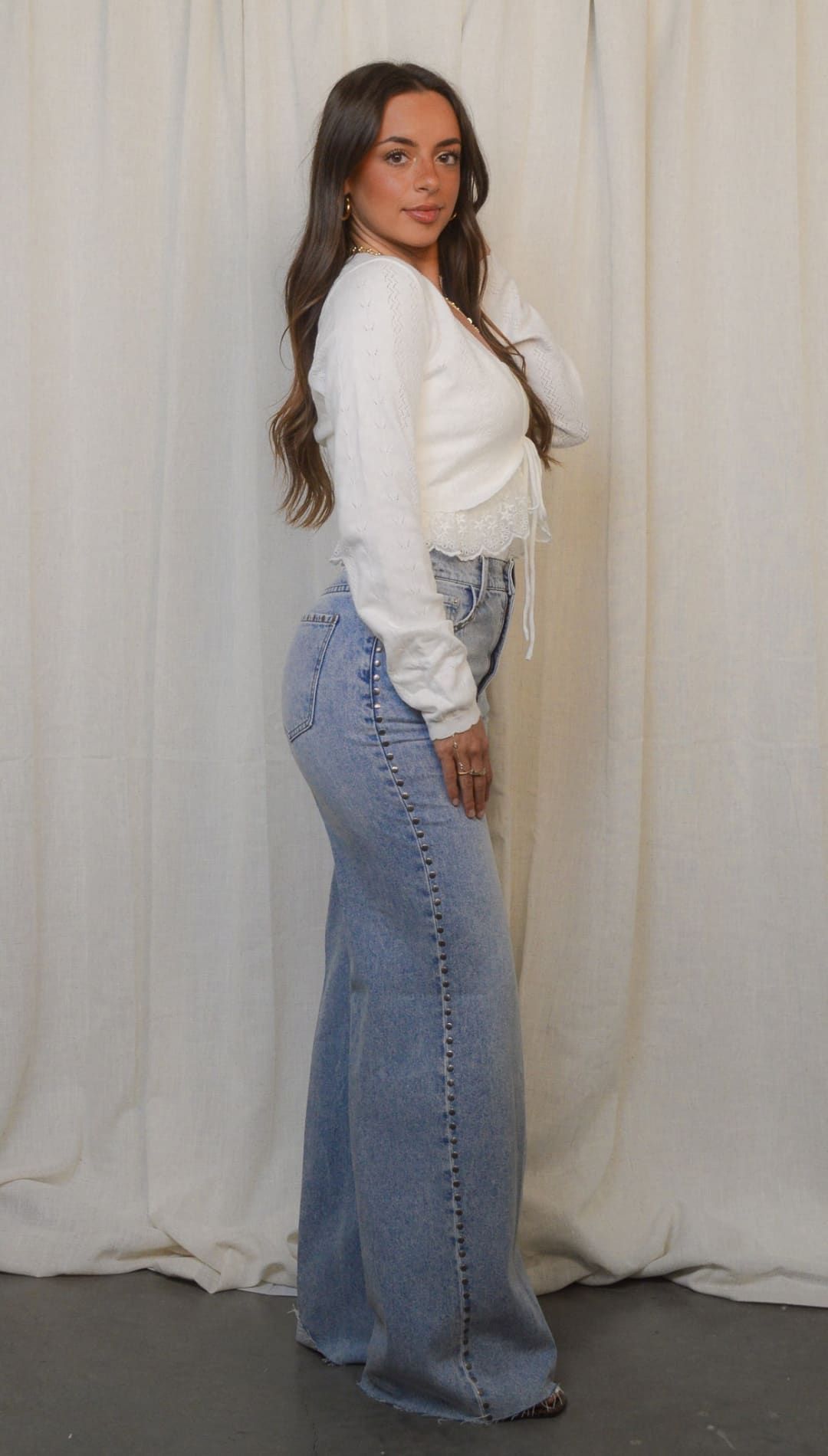Woman in white top and wide-leg jeans.