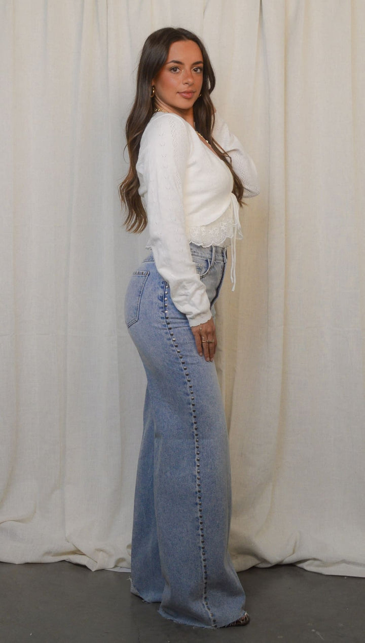 Woman in white top and wide-leg jeans.