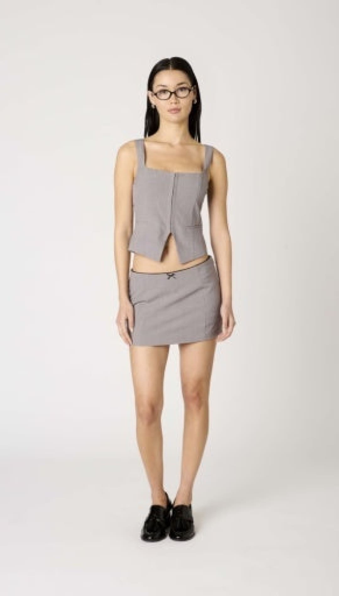A woman’s gray sleeveless top and matching mini skirt with black shoes.