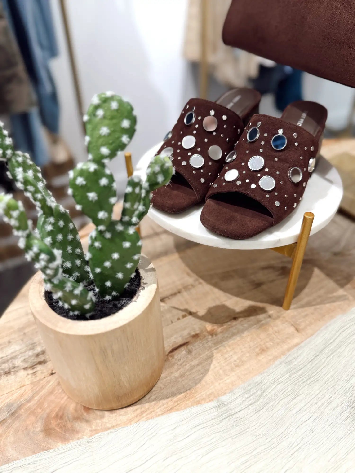 Brown suede slide sandals adorned with silver and blue circular studs.