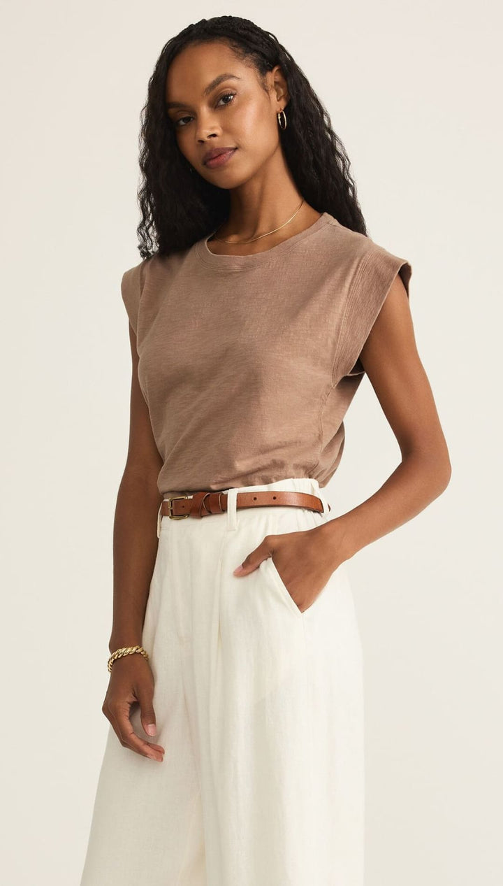 Woman wearing a brown top and white skirt.