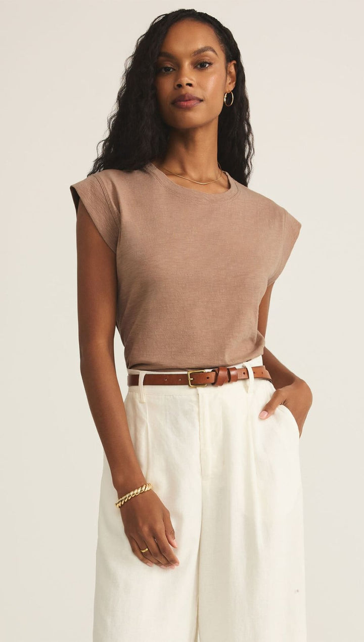 Woman in brown top and white pants.
