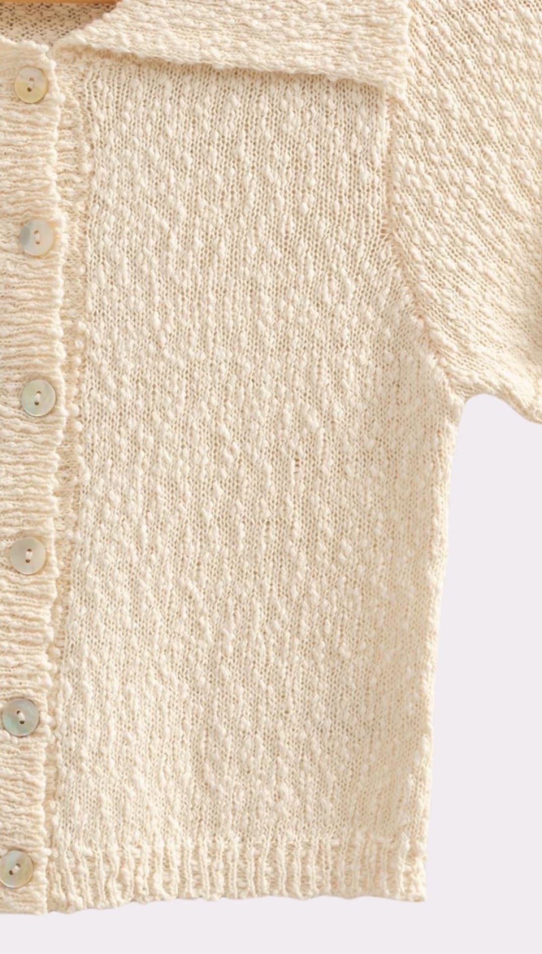 Cream-colored textured knit cardigan.