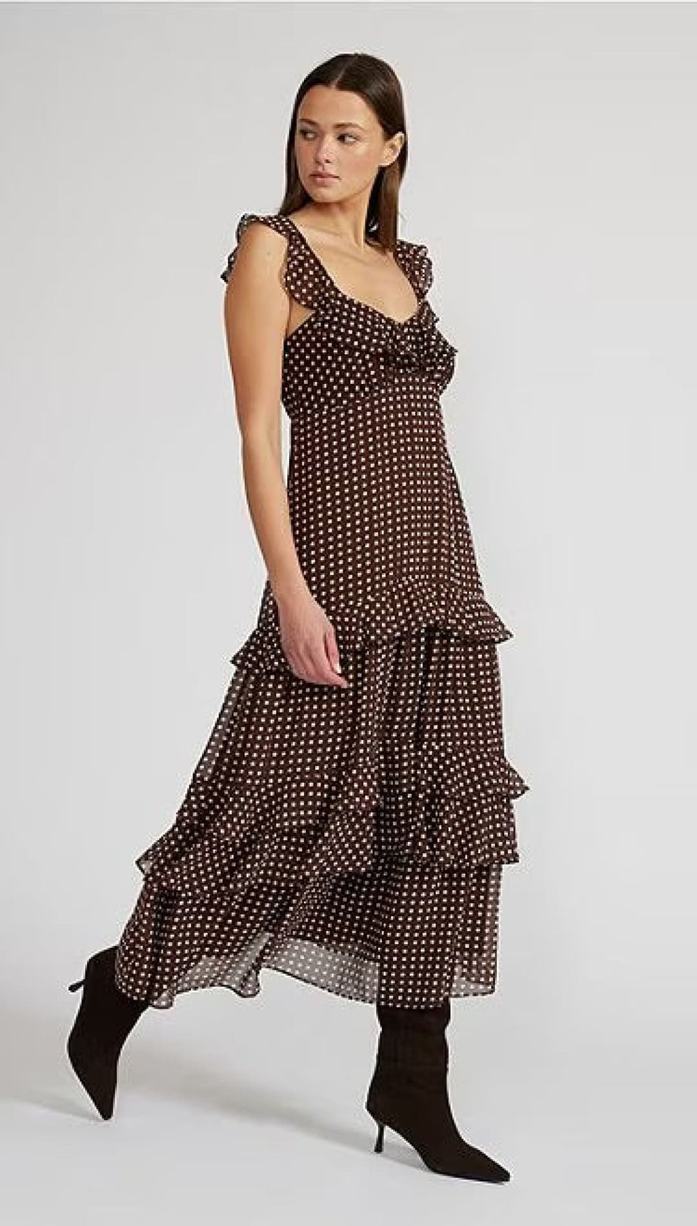 A woman’s tiered maxi dress with ruffles, a sweetheart neckline, and a dark base with white polka dots.