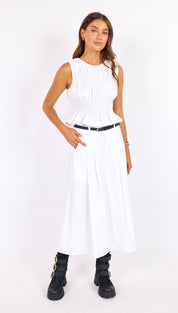 White sleeveless peplum dress with a gathered bodice and pleated skirt.