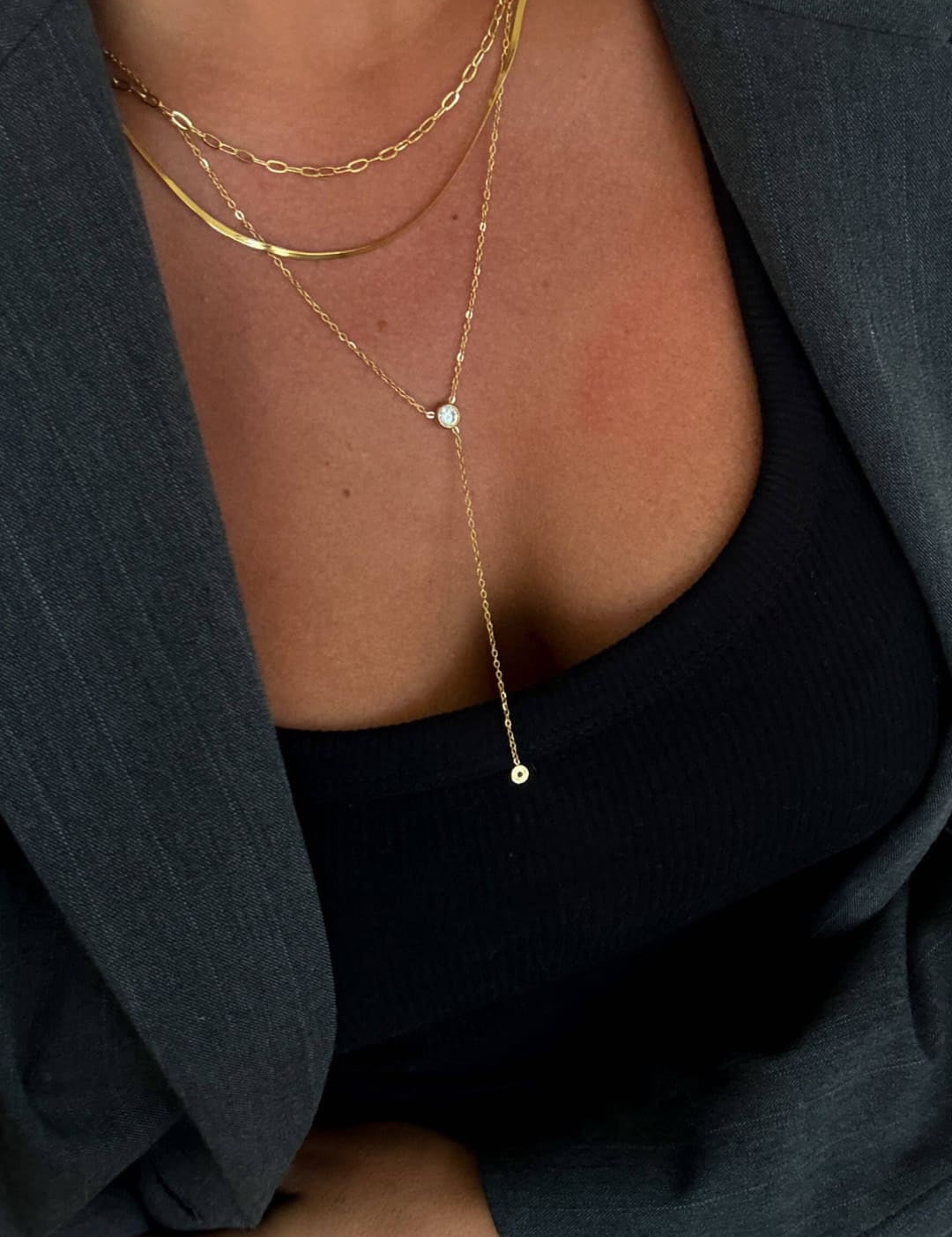 Gold chain necklace with a delicate drop pendant featuring two small round stones.