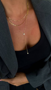 Gold chain necklace with a delicate drop pendant featuring two small round stones.