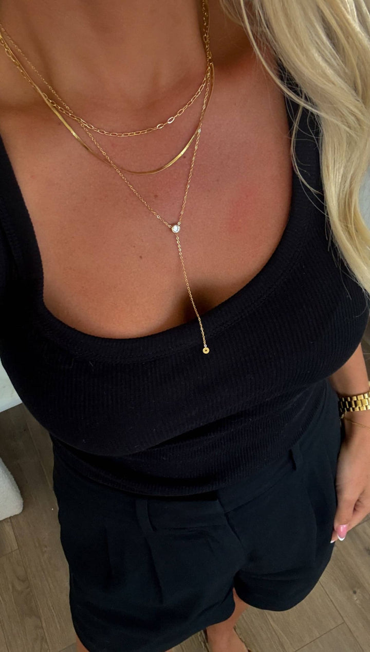 Gold layered necklaces with delicate chain links and dangling circular pendants