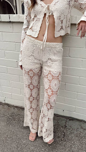 Cream-colored, intricately crocheted lace pants with a floral pattern and drawstring waist.
