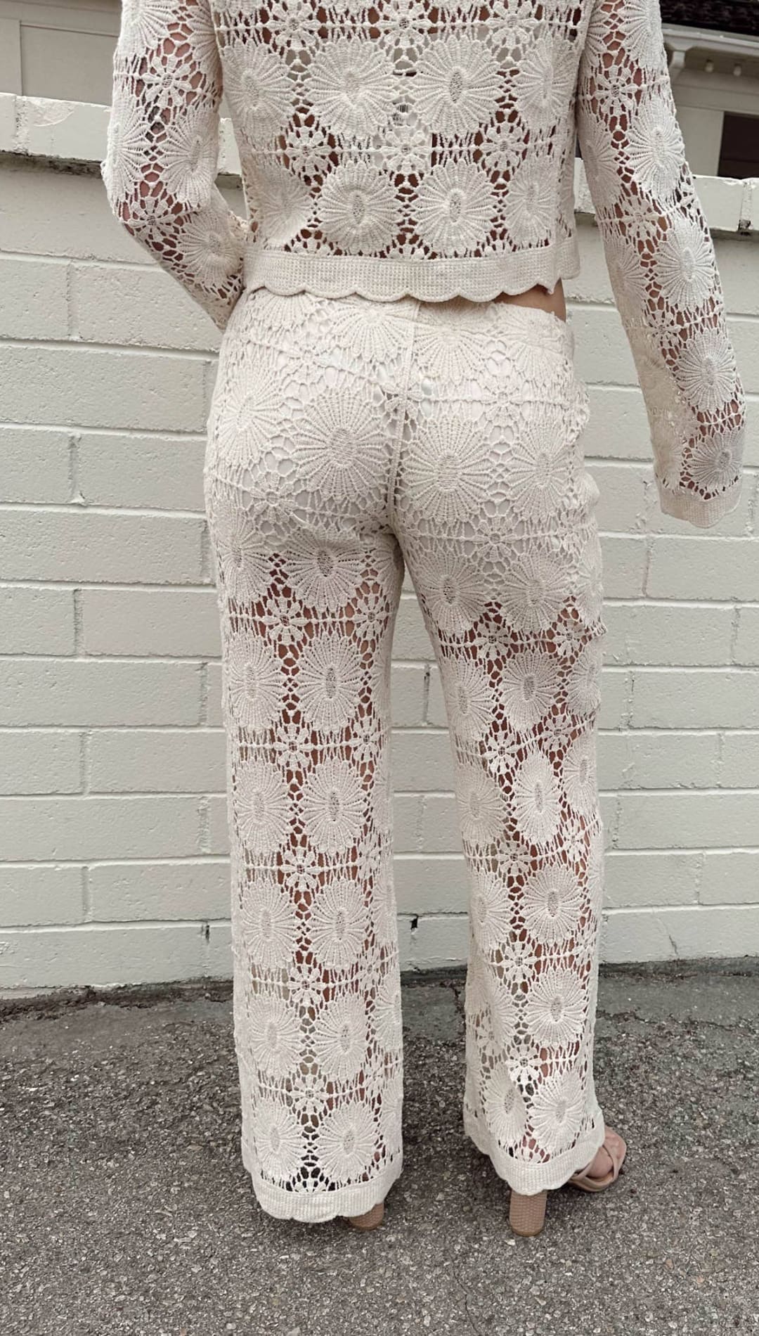 Cream-colored lace pants with a floral pattern and scalloped hem.