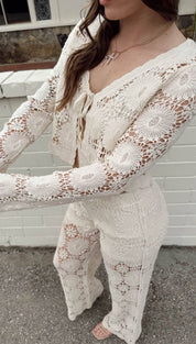 A delicate off-white crochet cardigan with intricate floral patterns and a matching cropped top.