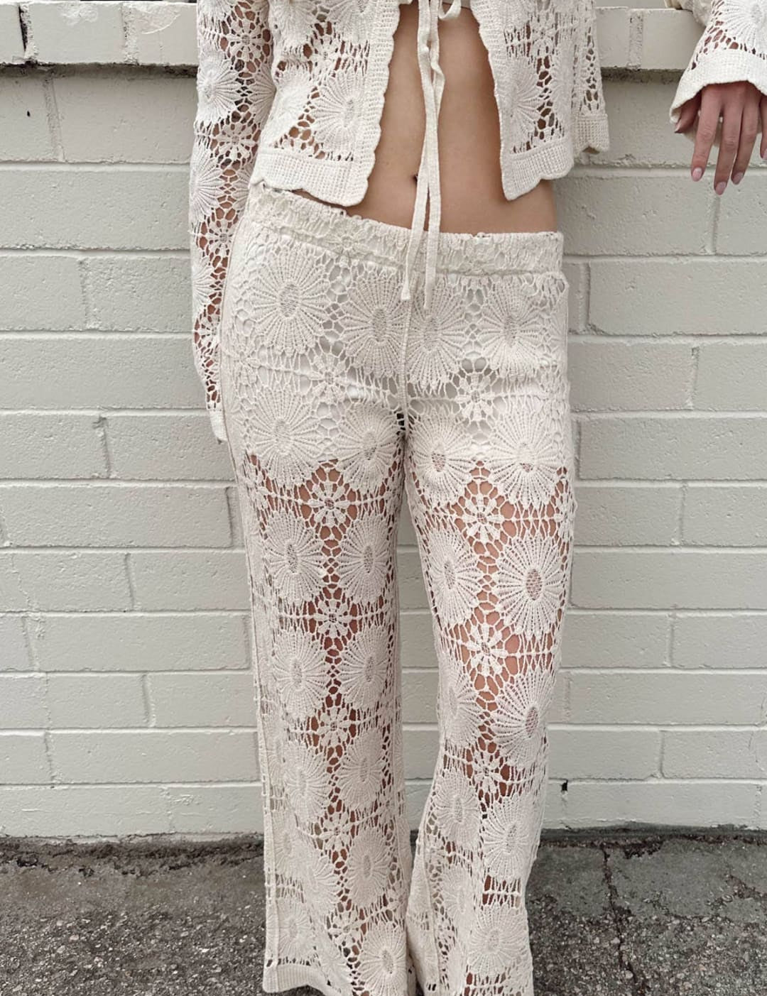 Cream-colored crochet knit two-piece set featuring intricate floral lace patterns and a matching tie-front cardigan.