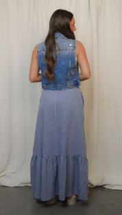 Woman in denim vest and gingham dress.