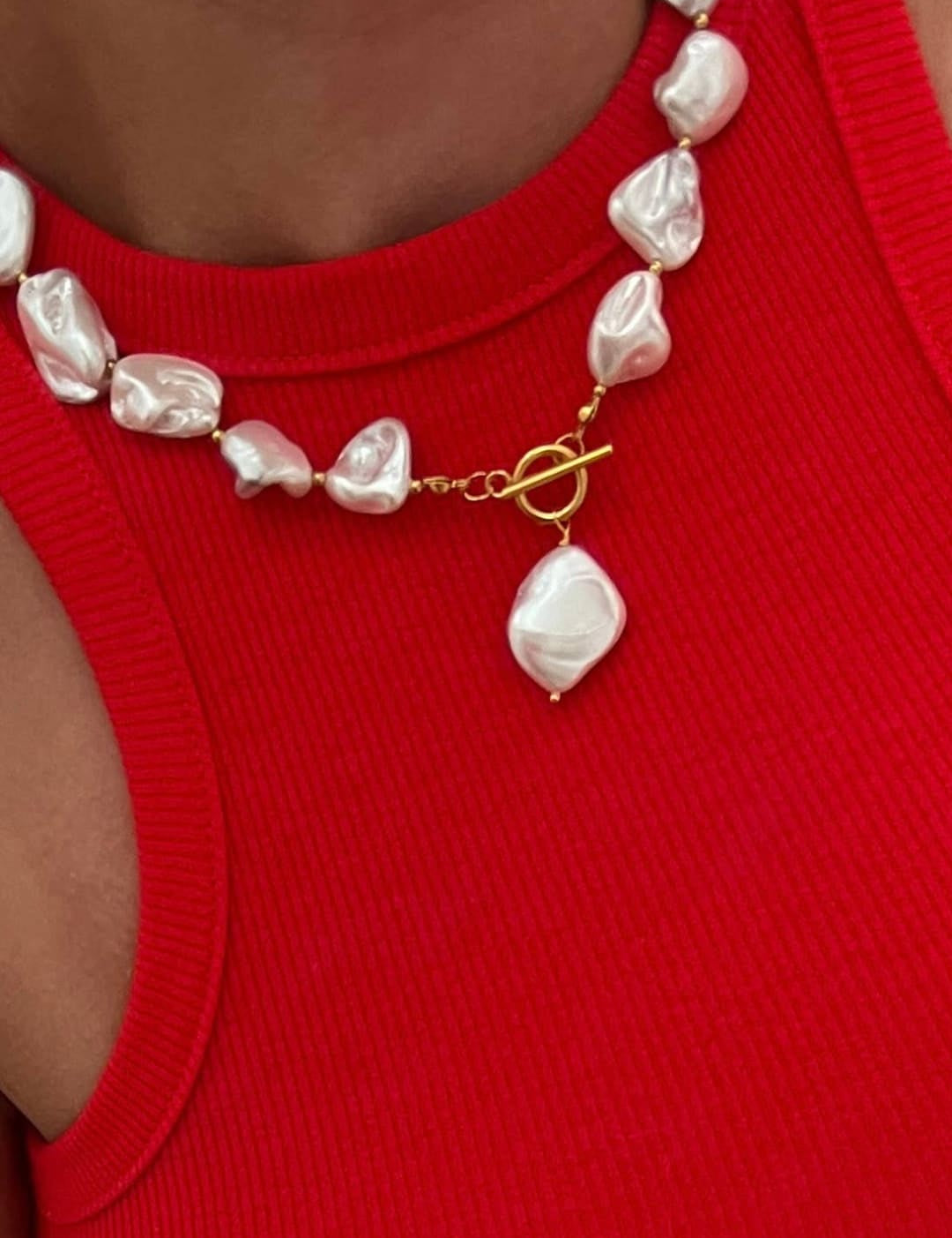 A delicate necklace featuring irregularly shaped, lustrous white pearls strung together with a gold-toned toggle clasp and a matching dangling pearl pendant.