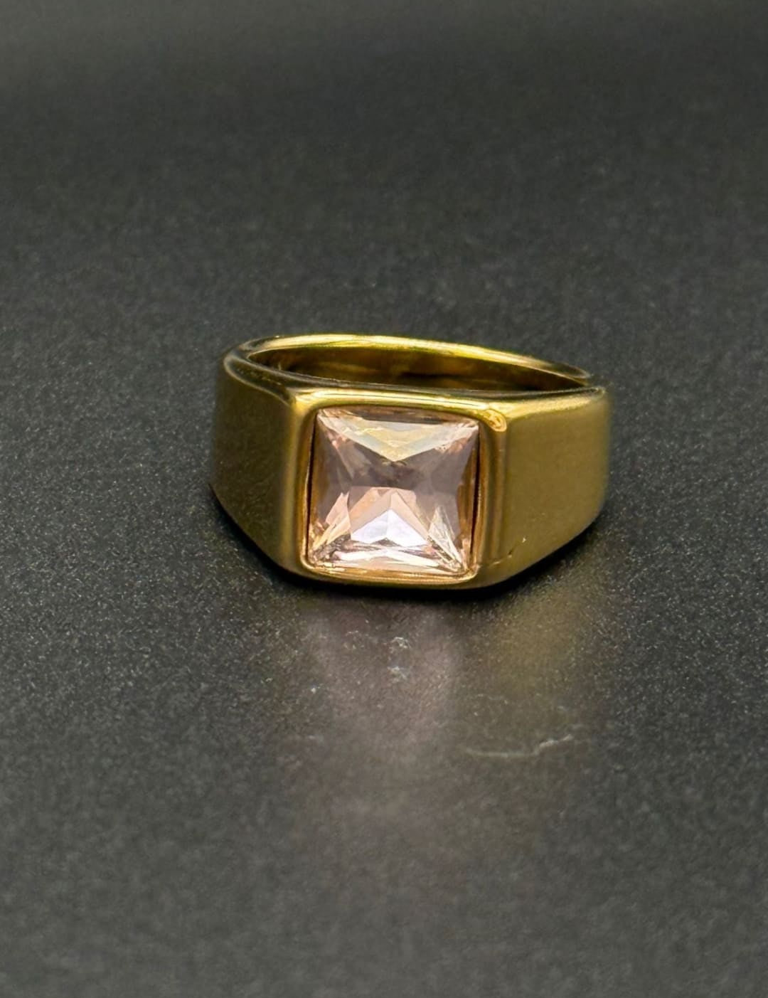 Gold ring with square pink gemstone.