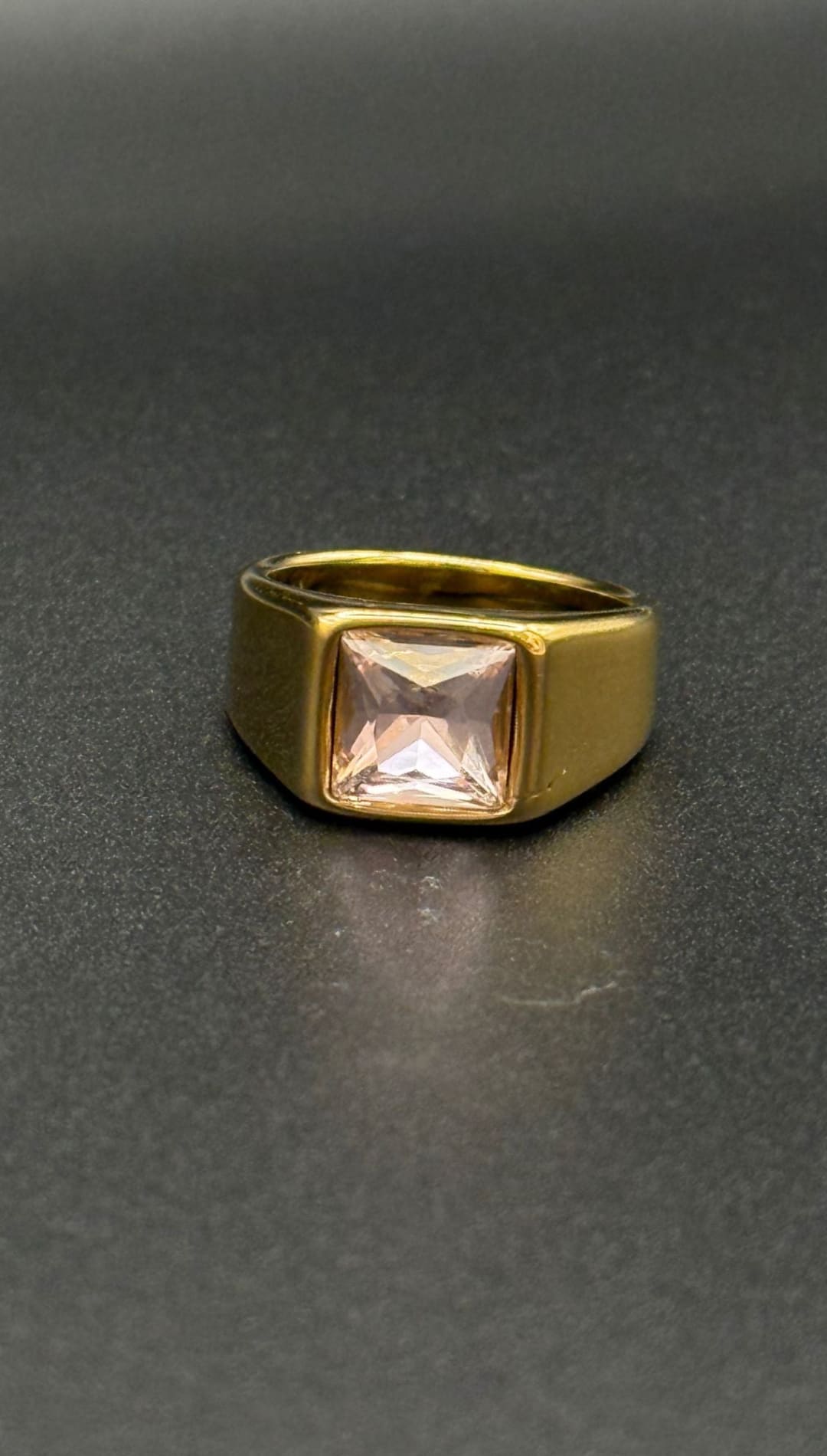 Gold ring with square pink gemstone.