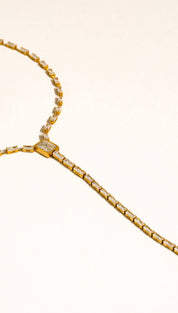 Gold-toned lariat necklace featuring a central square-cut diamond accent and elongated baguette-shaped stones set in a sleek, minimalist design.