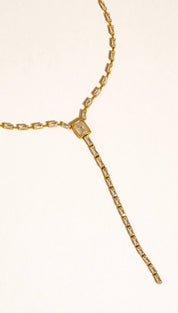 Gold-toned lariat necklace featuring a central rectangular diamond accent and elongated baguette-cut stones along the chain.