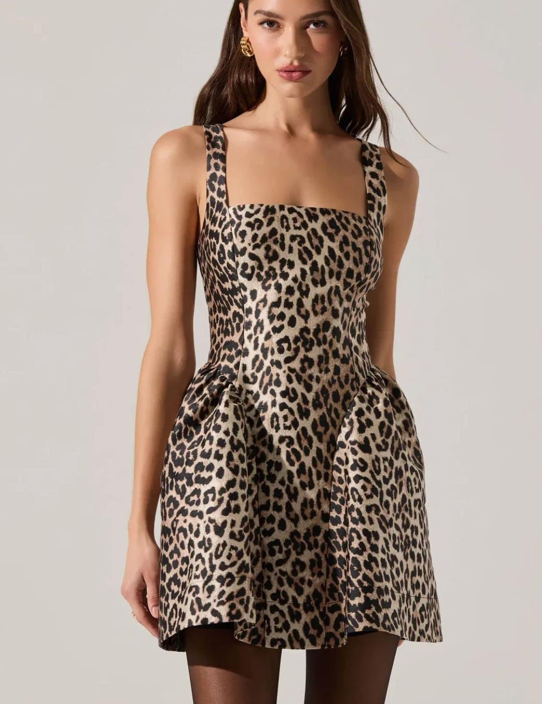 A sleeveless, leopard print mini dress with a square neckline and a full skirt with pockets.