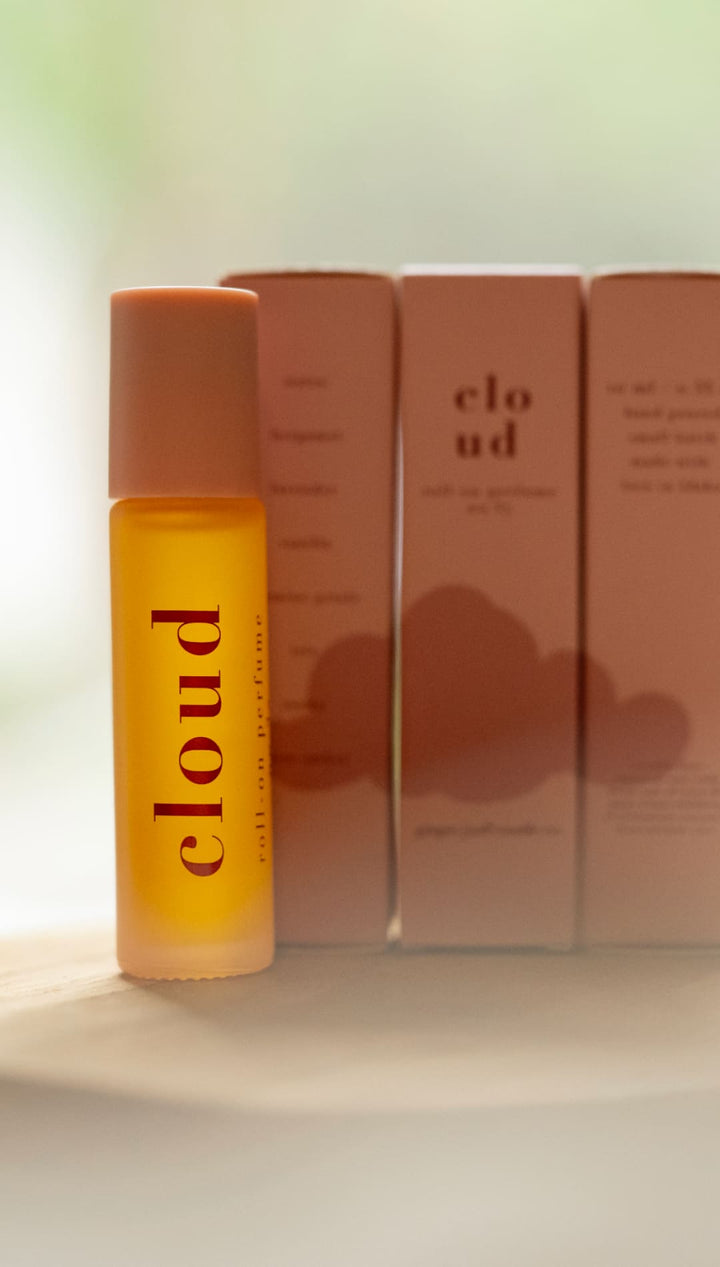 Cloud perfume bottle with orange cap and pink box.