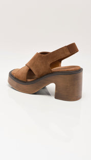 Brown suede platform sandal with a chunky wooden heel and crisscross strap design.