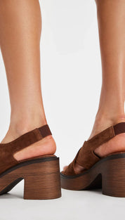 Brown suede platform sandals with a chunky wooden heel and adjustable ankle strap.