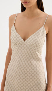 A beige slip dress with a subtle geometric pattern and delicate spaghetti straps.