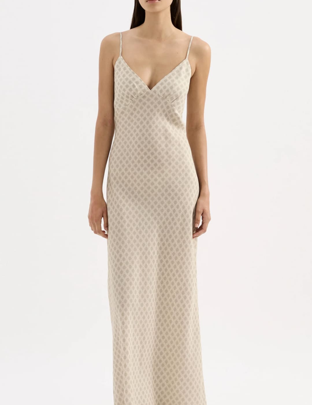 A flowing, off-white slip dress with a subtle geometric pattern and delicate spaghetti straps.