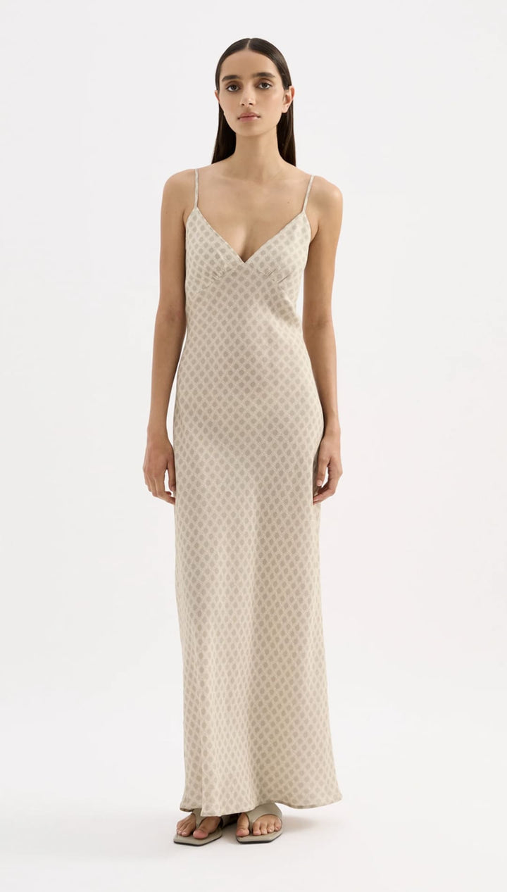 A flowing, off-white slip dress with a subtle geometric pattern and delicate spaghetti straps.