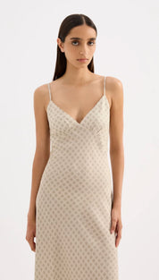A flowing, off-white slip dress with delicate spaghetti straps and a subtle polka dot pattern.