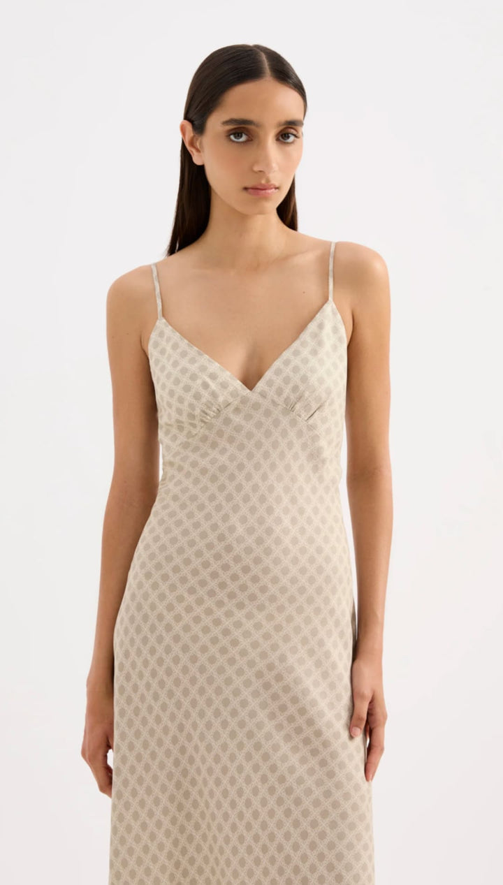 A flowing, off-white slip dress with delicate spaghetti straps and a subtle polka dot pattern.