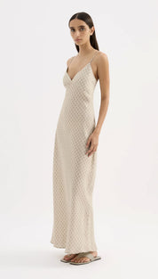 A flowing, off-white slip dress with a subtle geometric pattern and delicate spaghetti straps.